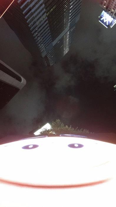 Smiley Times Square, 2007 — upward view in Times Square, New York, with a large illuminated smiley face and skyscrapers rising into a hazy night sky, by Hannes Bend