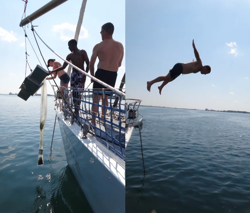 Crew on the bow of the sailing vessel Sea Dragon lowering a sampling net, beside a person diving into open water.