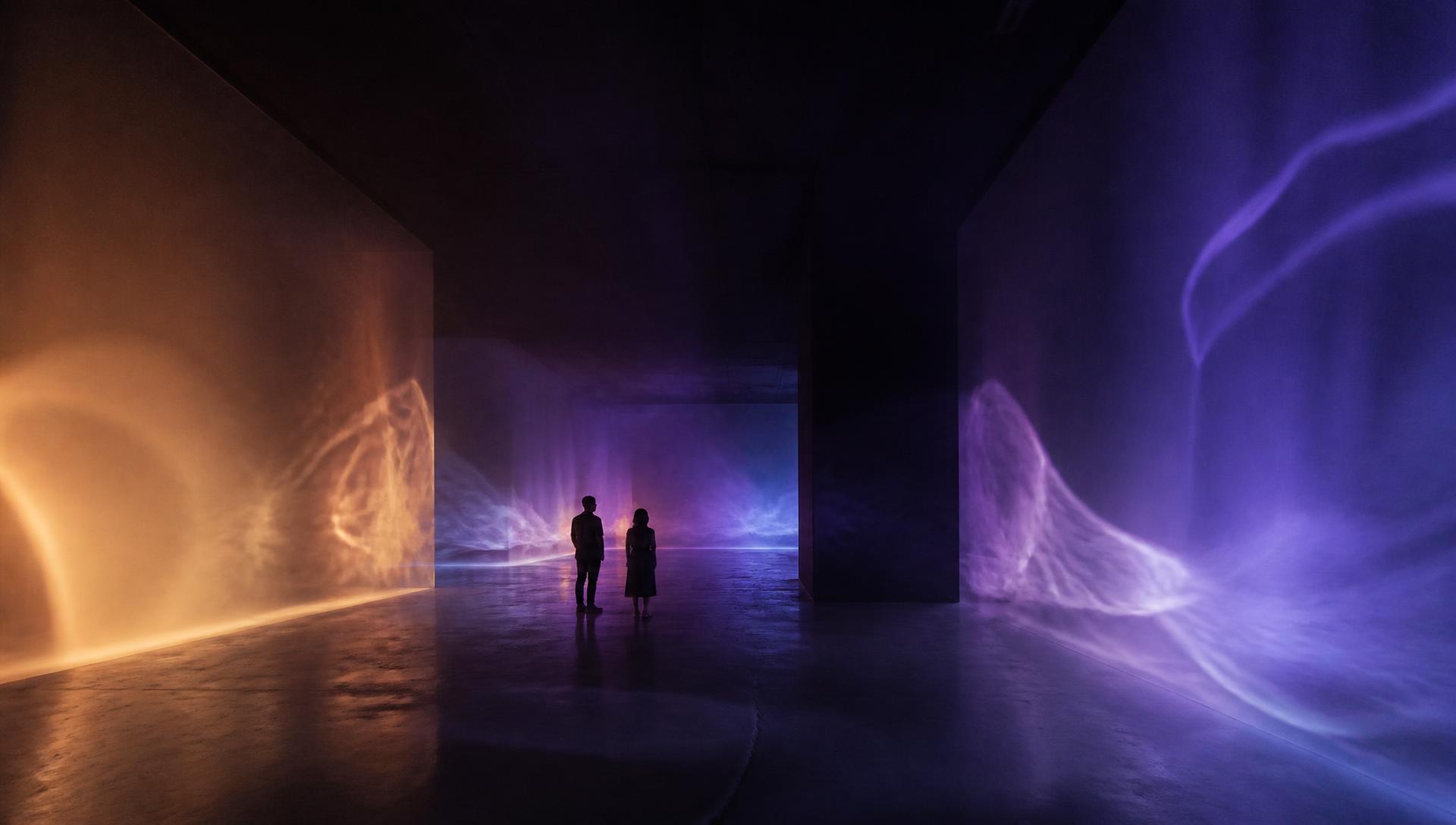 AutonoME, 2019/2026 — a wide view of the darkened gallery with luminous violet, blue and amber fields receding into depth while slow translucent veils of haze drift through the space, with two visitors at architectural scale