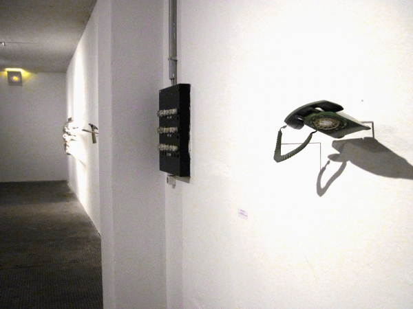 Satellites in the Night, 2010, Freies Museum Berlin — installation view: a distorted rotary telephone protruding from the wall (Robert Lazzarini, right) and a wall-embedded hammer work (Jomar Statkun, left)
