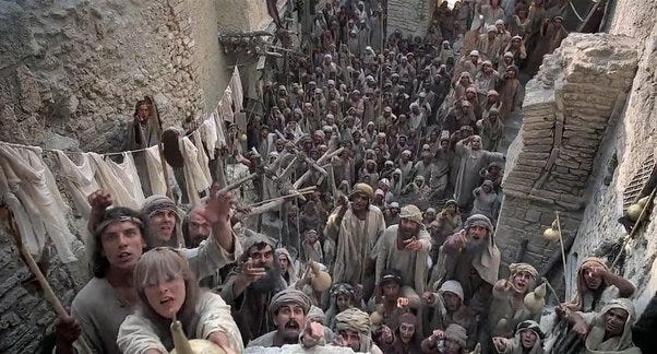 Still from Monty Python's Life of Brian: a crowd in a narrow street looking up at a figure on a balcony.
