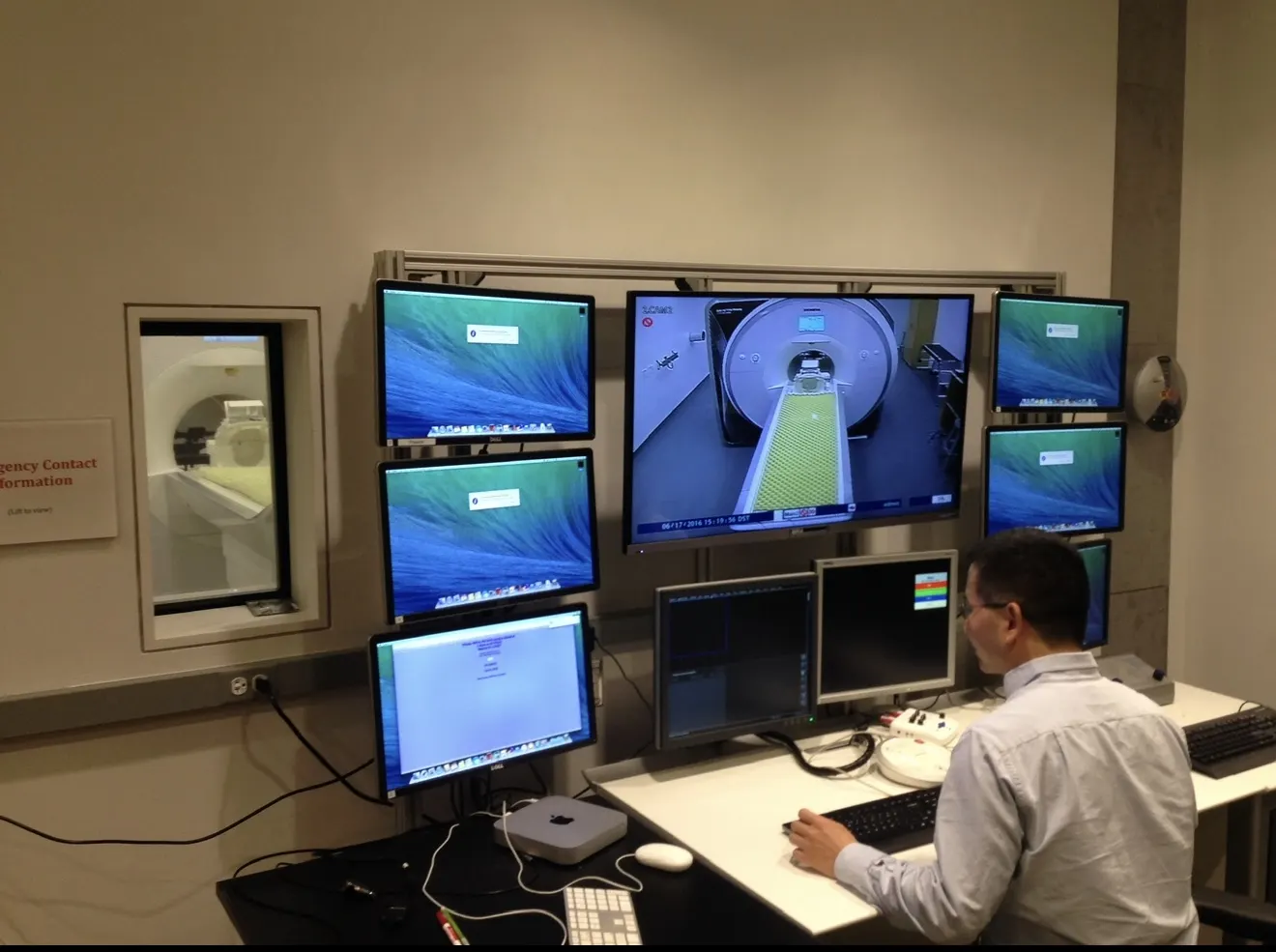 MRI control room with brain-scan images displayed across computer monitors.