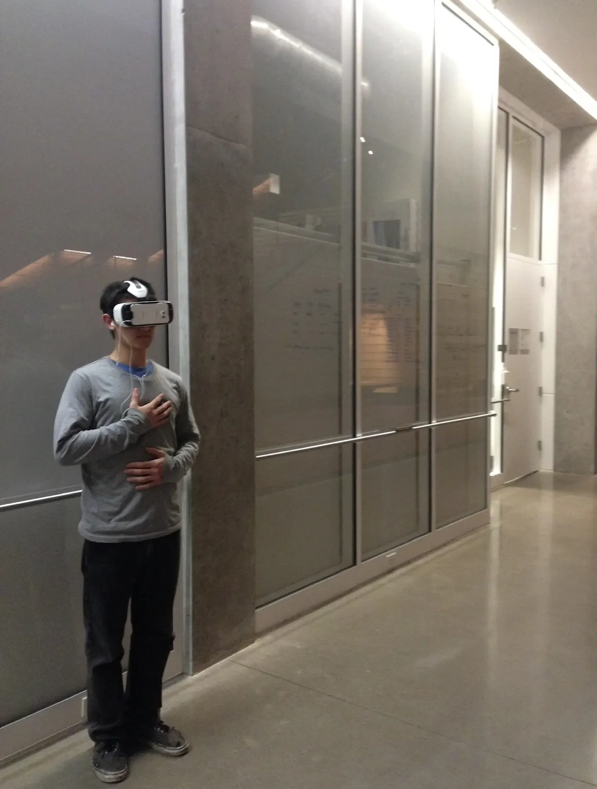 Participant wearing a VR headset and touching their chest inside the Lewis Integrative Science Building.