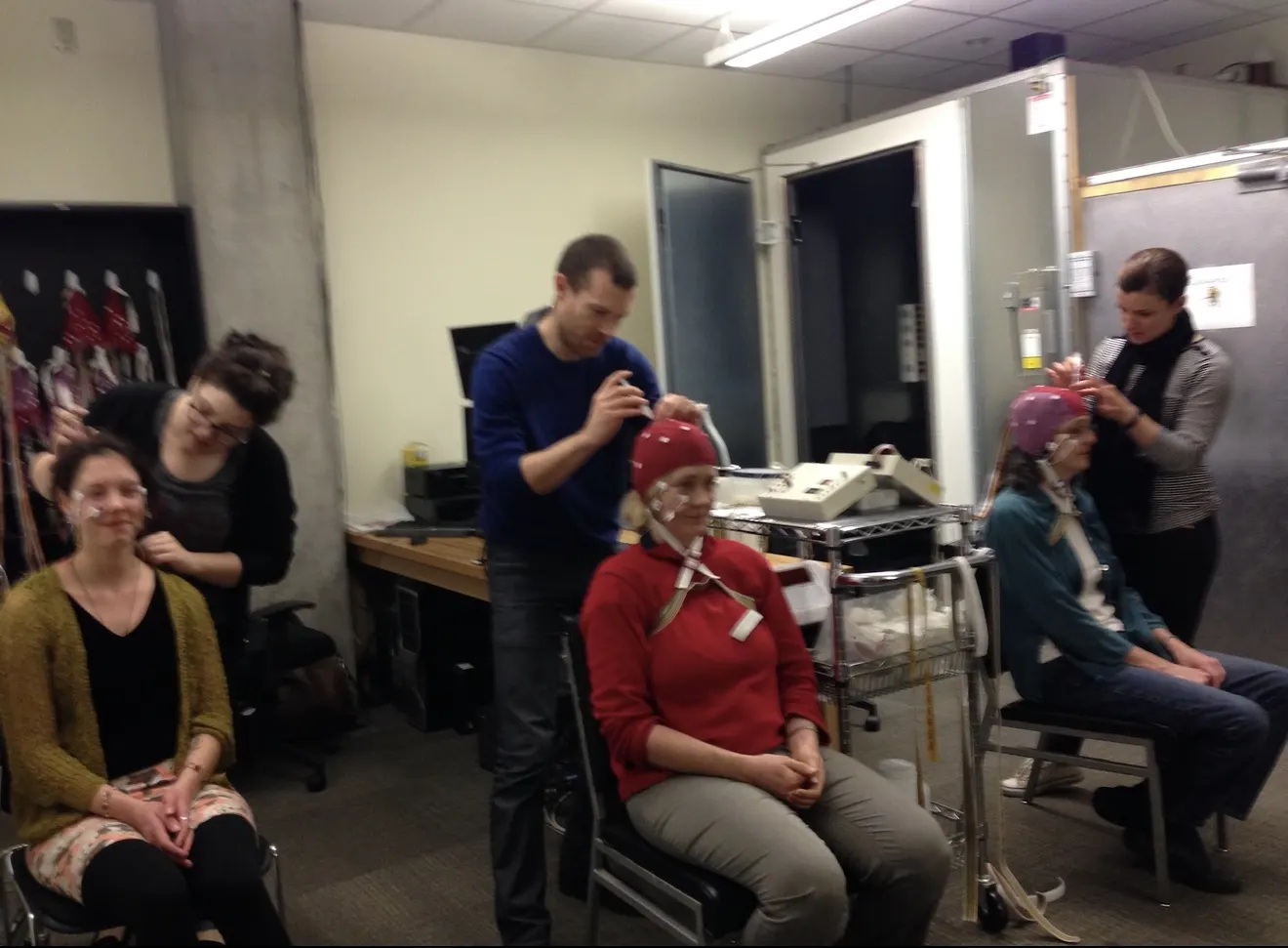 Researchers fitting EEG caps to seated participants in a University of Oregon laboratory.
