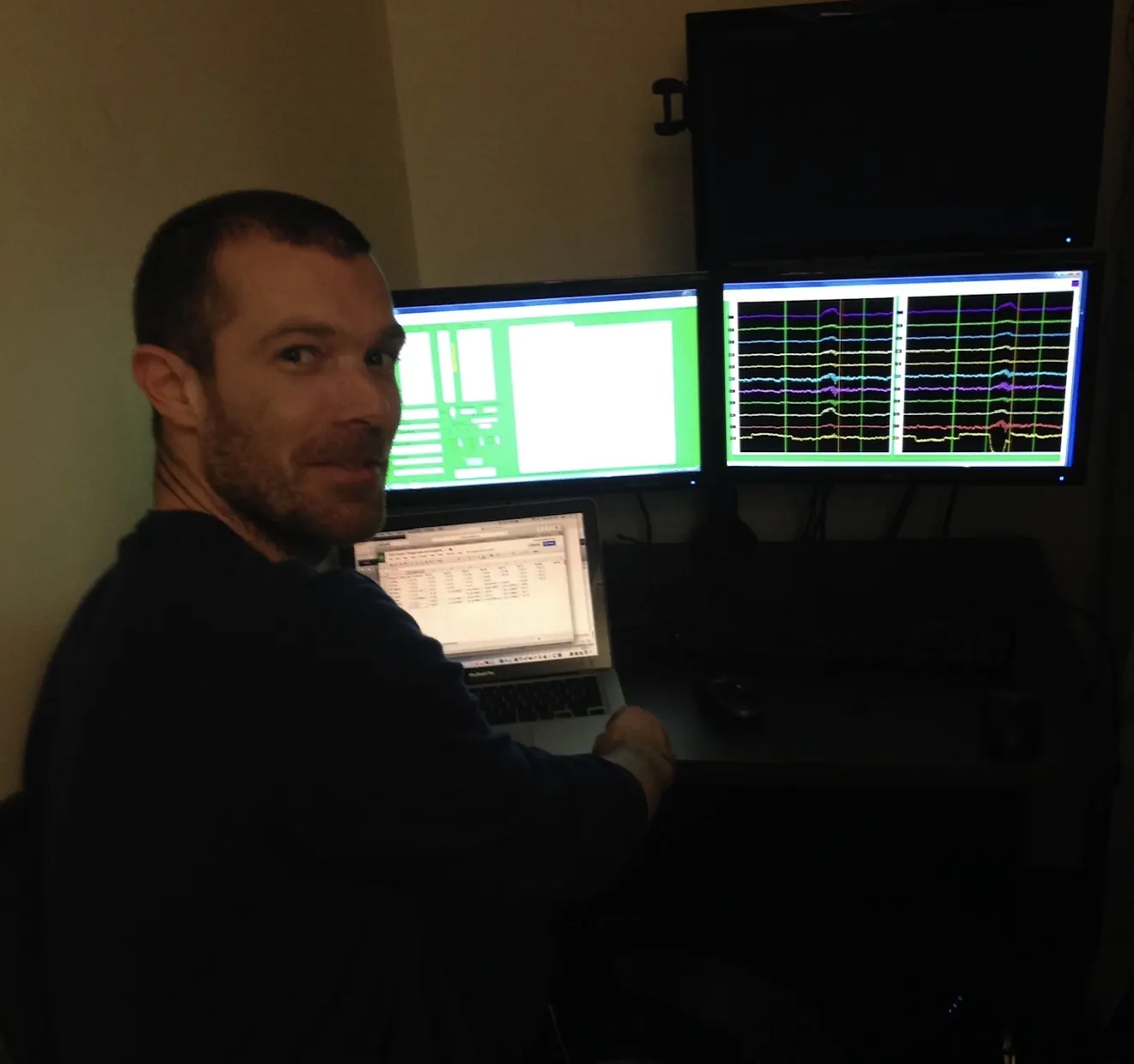 Hannes Bend at an EEG monitoring workstation displaying multichannel brain-wave traces, University of Oregon.